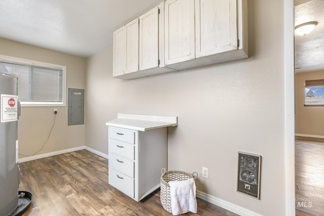 washroom with dark hardwood / wood-style flooring, electric panel, and water heater