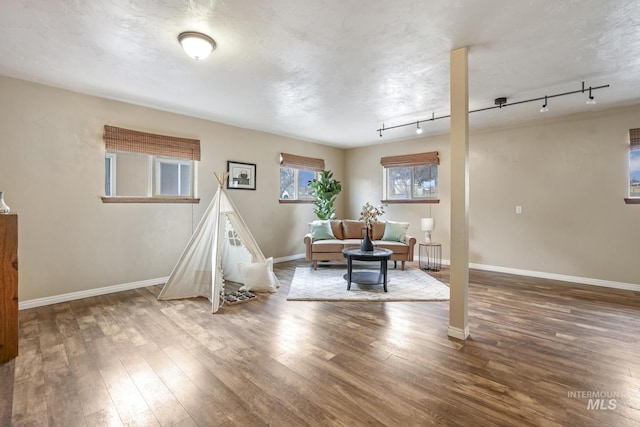 rec room with hardwood / wood-style floors, track lighting, and a textured ceiling