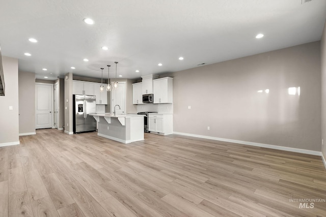 unfurnished living room featuring baseboards, recessed lighting, light wood-type flooring, and a sink