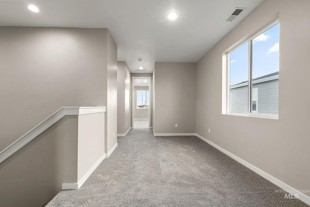 interior space with visible vents, carpet floors, baseboards, and an upstairs landing