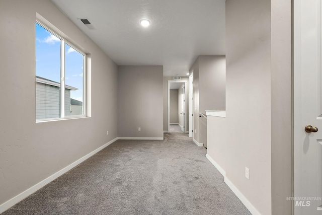 carpeted spare room with visible vents and baseboards