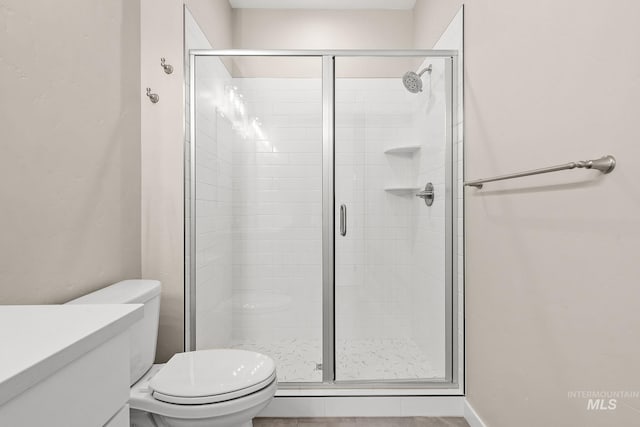 bathroom featuring vanity, a shower stall, and toilet