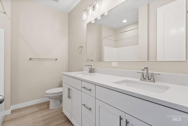 full bath featuring a sink, baseboards, toilet, and wood finished floors