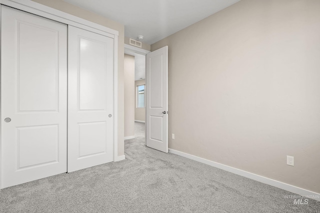 unfurnished bedroom featuring visible vents, carpet, baseboards, and a closet