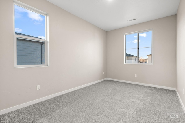 carpeted empty room featuring baseboards and visible vents