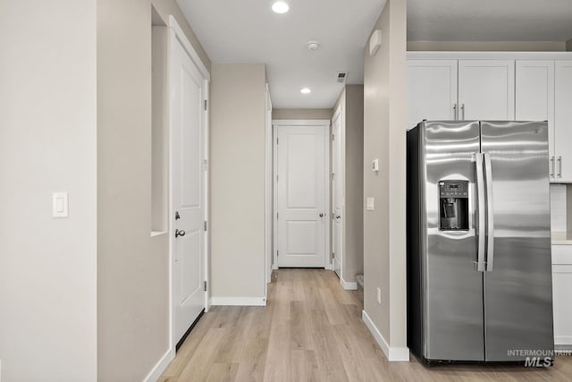 kitchen featuring stainless steel refrigerator with ice dispenser, white cabinetry, recessed lighting, light wood-style floors, and baseboards