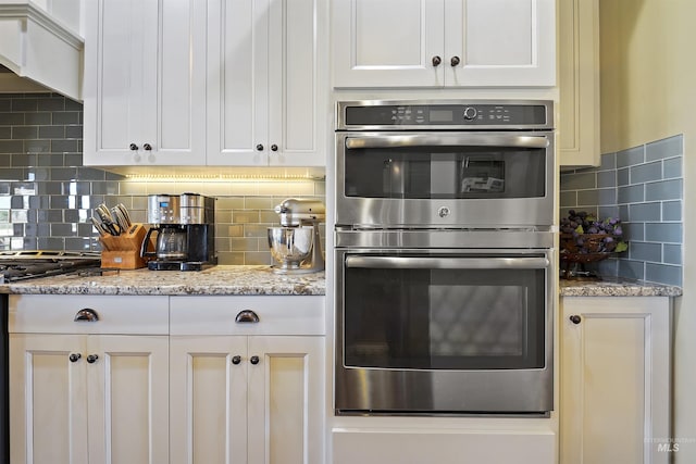 kitchen with appliances with stainless steel finishes, white cabinets, premium range hood, and decorative backsplash