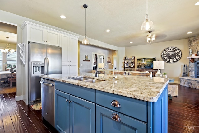 kitchen featuring blue cabinets, stainless steel appliances, a sink, and open floor plan