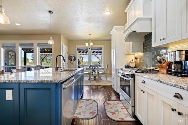 kitchen featuring a center island with sink, blue cabinetry, appliances with stainless steel finishes, dark wood-type flooring, and a sink