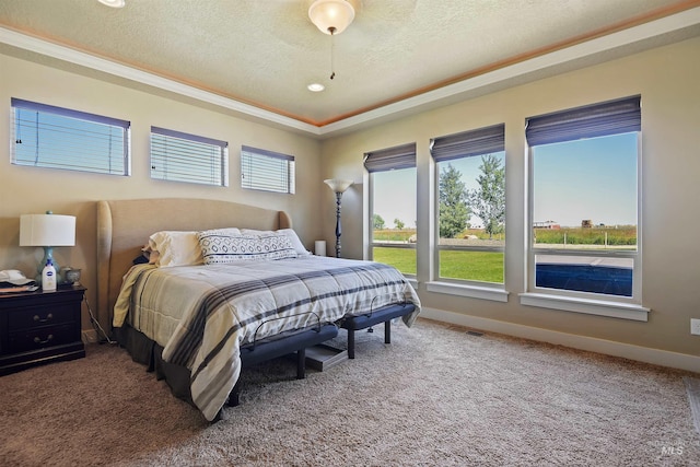 bedroom featuring light carpet, a textured ceiling, and baseboards