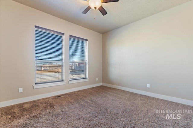 carpeted empty room with ceiling fan, a textured ceiling, visible vents, and baseboards