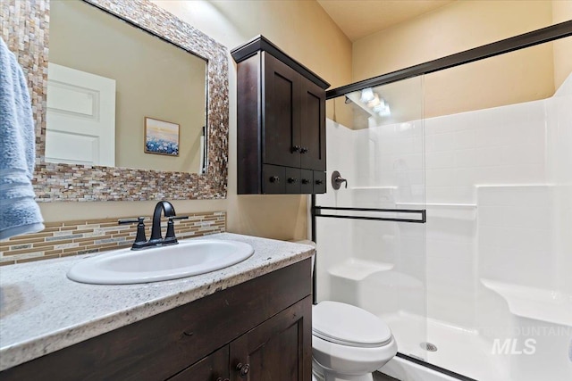 bathroom featuring toilet, a shower stall, tasteful backsplash, and vanity