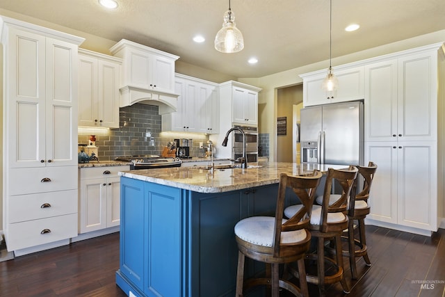 kitchen with dark wood-style flooring, stainless steel refrigerator with ice dispenser, a sink, light stone countertops, and range