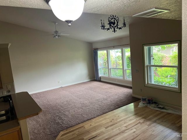 spare room with carpet, ceiling fan, vaulted ceiling, and a textured ceiling