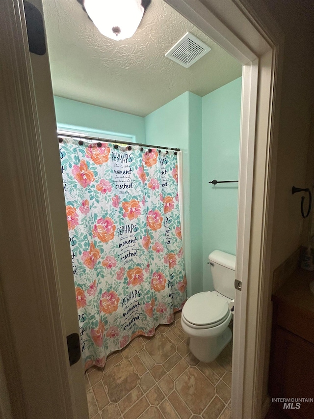 bathroom with a textured ceiling, toilet, and tile patterned floors