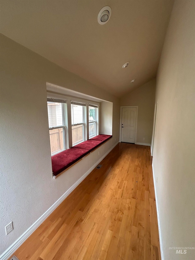 unfurnished room with light hardwood / wood-style flooring and lofted ceiling