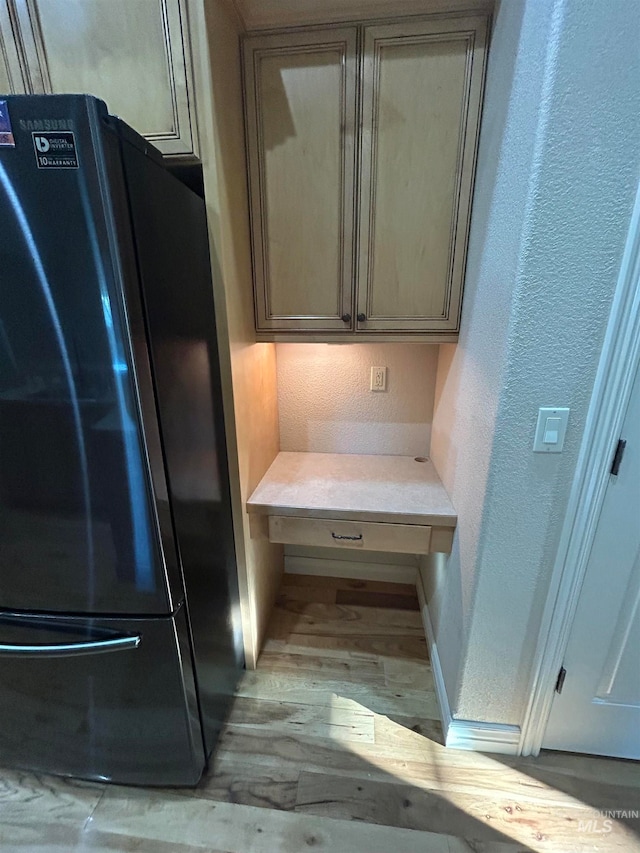 room details with black fridge and light hardwood / wood-style floors