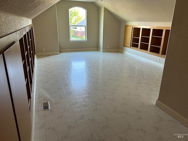 bonus room with vaulted ceiling, built in features, light tile patterned floors, and a textured ceiling