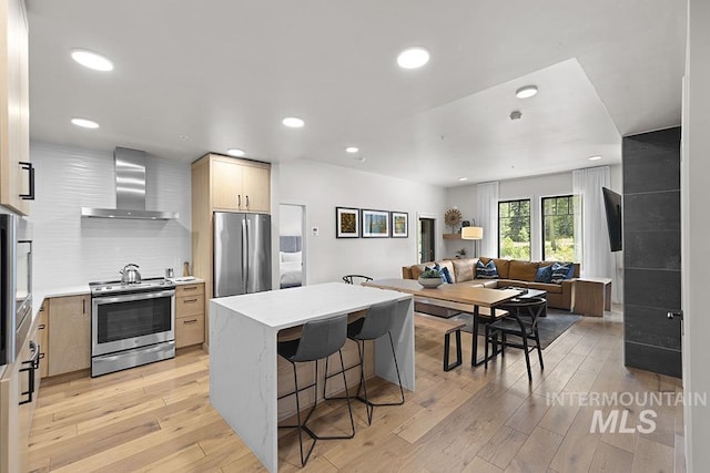 720 Village Dr Unit 404, Donnelly, ID 83615 - kitchen featuring appliances with stainless steel finishes, wall chimney exhaust hood, open floor plan, a breakfast bar, and light wood-type flooring