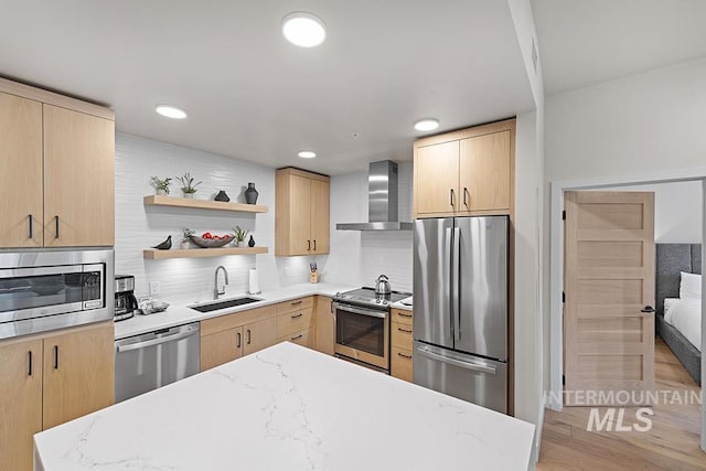 720 Village Dr Unit 404, Donnelly, ID 83615 - kitchen with appliances with stainless steel finishes, light brown cabinetry, a sink, wall chimney range hood, and backsplash