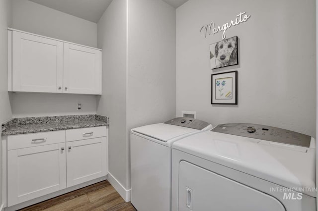 laundry area with washer and dryer, cabinet space, and wood finished floors