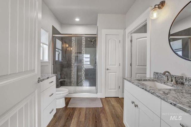 full bath with a shower stall, vanity, wood finished floors, toilet, and recessed lighting