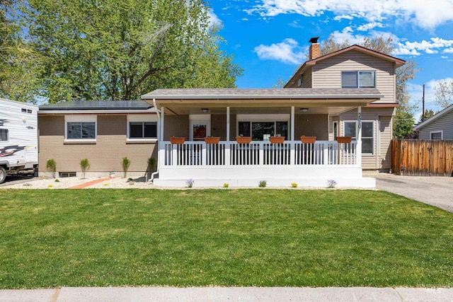 view of front of property featuring a chimney, a porch, a front lawn, and brick siding