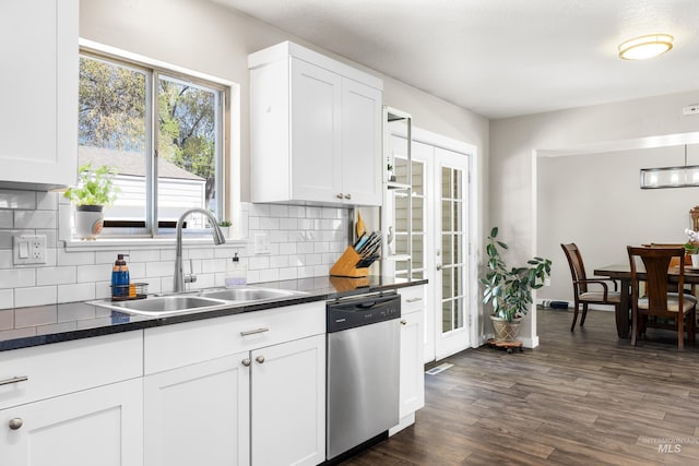 kitchen featuring dark countertops, tasteful backsplash, dishwasher, a sink, and white cabinetry
