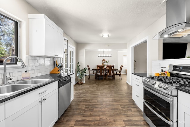kitchen with dark countertops, appliances with stainless steel finishes, a sink, extractor fan, and decorative backsplash