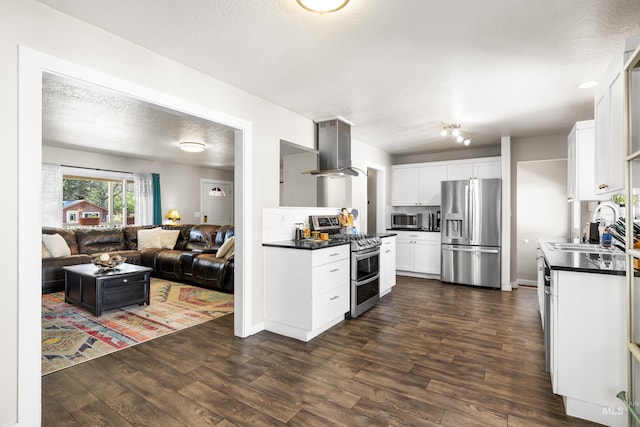 kitchen with dark countertops, a sink, extractor fan, stainless steel appliances, and open floor plan