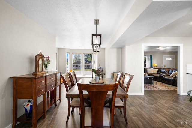 dining space with baseboards, a textured ceiling, and dark wood-type flooring