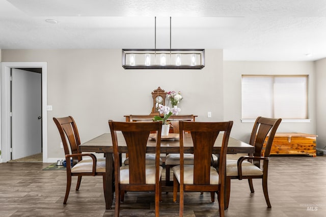 dining space with baseboards, a textured ceiling, and dark wood-style floors