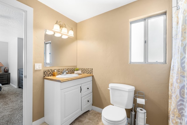 bathroom with a healthy amount of sunlight, vanity, decorative backsplash, and toilet