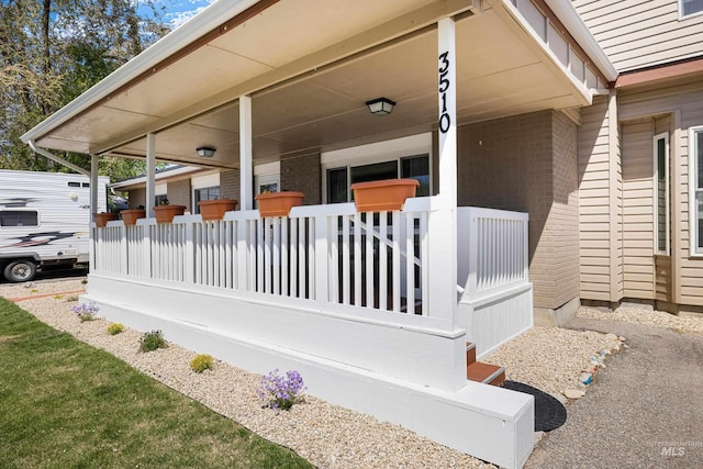 view of side of home with a porch and brick siding