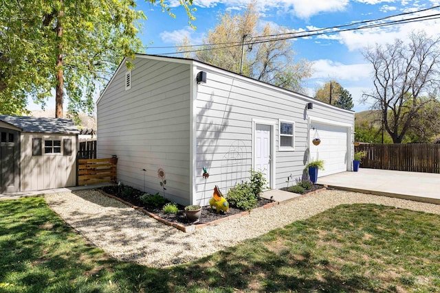 garage featuring fence and concrete driveway