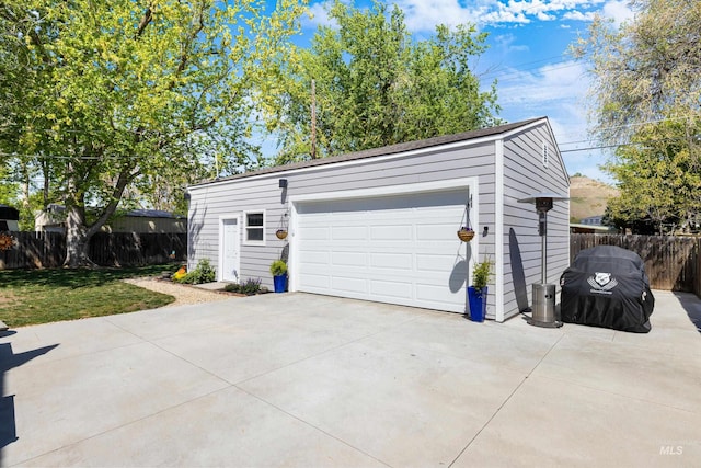 garage with concrete driveway and fence