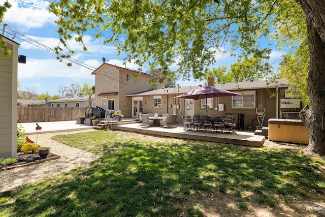 rear view of property with a lawn, a deck, a hot tub, fence, and outdoor lounge area