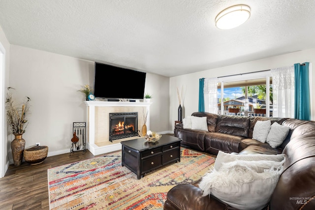 living area with baseboards, a fireplace, a textured ceiling, and wood finished floors