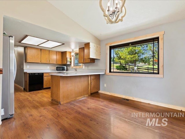 kitchen featuring light countertops, stainless steel appliances, wood finished floors, and a peninsula