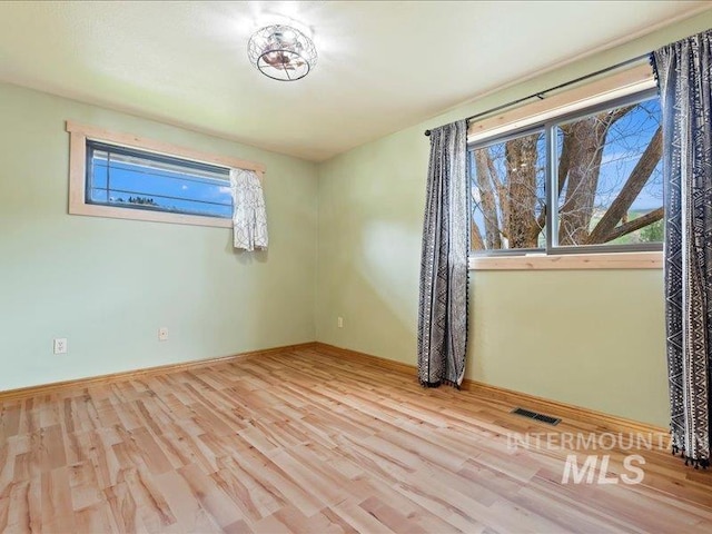 spare room featuring visible vents, baseboards, and wood finished floors
