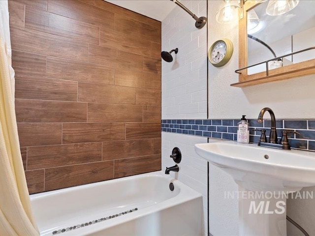 bathroom with tile walls, decorative backsplash, a sink, and shower / tub combo