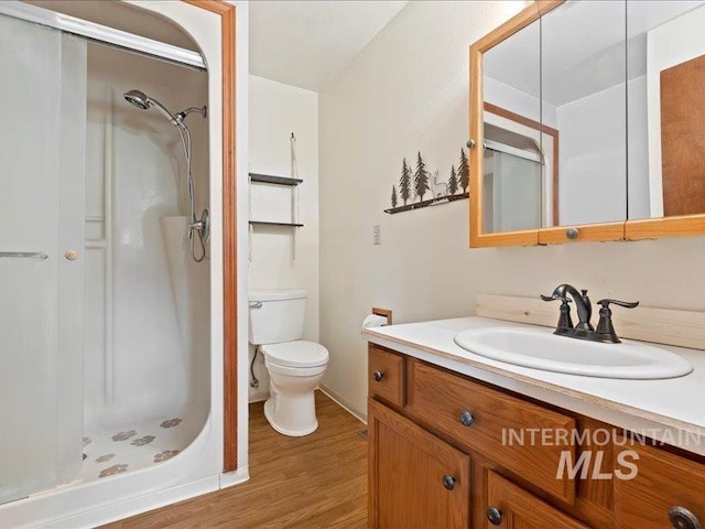 full bathroom featuring vanity, a stall shower, wood finished floors, and toilet