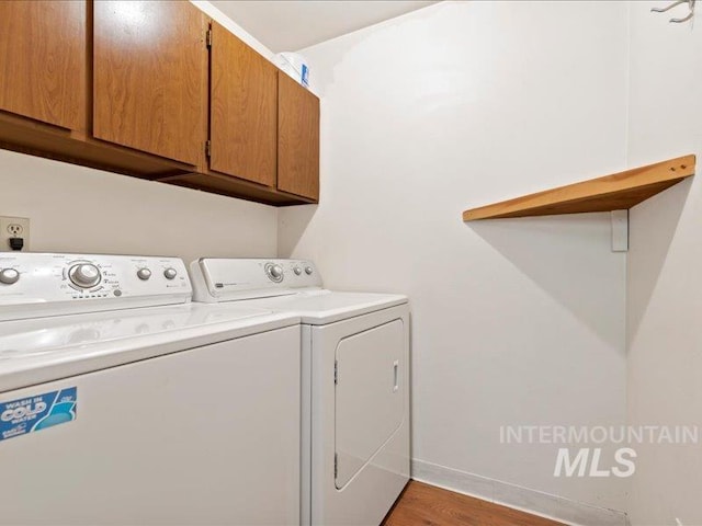 laundry room with separate washer and dryer, baseboards, cabinet space, and wood finished floors