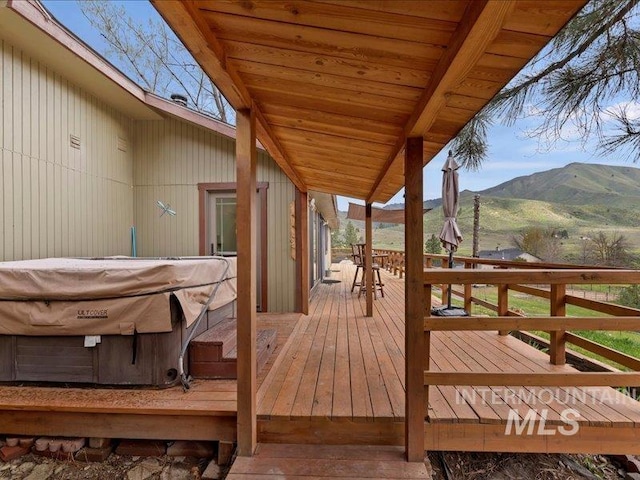 deck with a hot tub and a mountain view