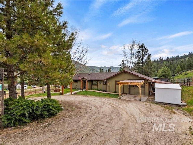 single story home featuring fence, curved driveway, a mountain view, and an attached garage