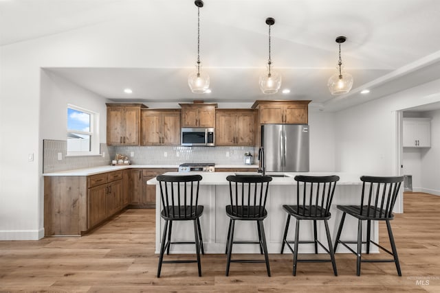 kitchen with appliances with stainless steel finishes, lofted ceiling, and light hardwood / wood-style flooring