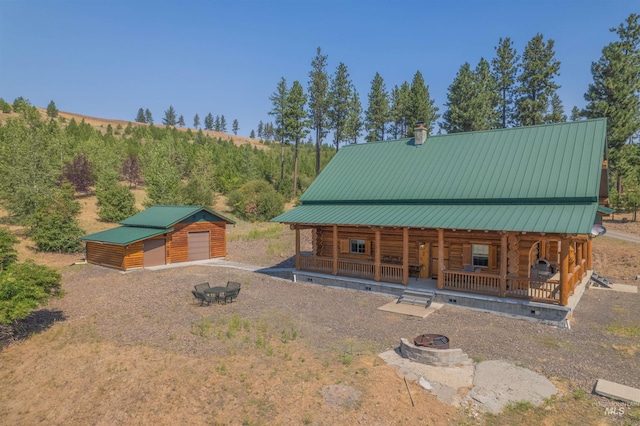 view of front facade with covered porch, an outdoor structure, and an outdoor fire pit