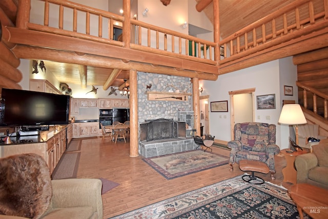 living room featuring beam ceiling, a high ceiling, wood-type flooring, a fireplace, and wood ceiling
