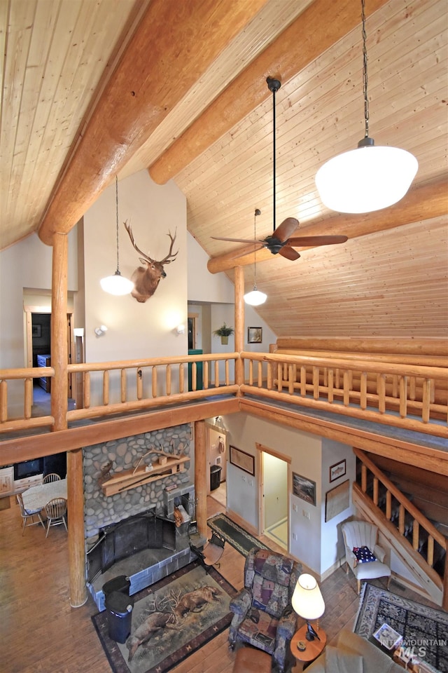 interior space featuring hardwood / wood-style floors, beam ceiling, a stone fireplace, and wood ceiling