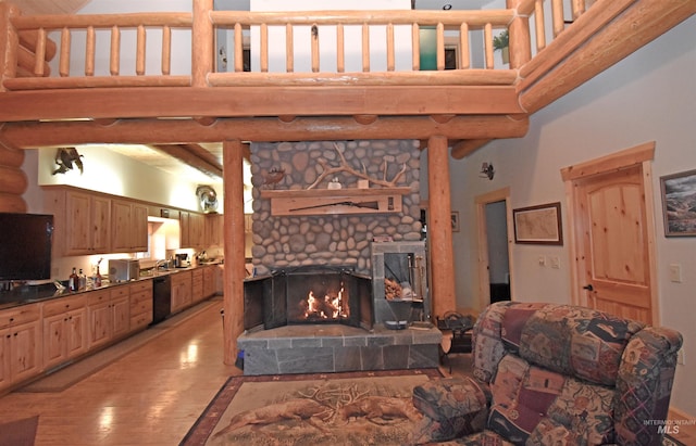 living room featuring a stone fireplace, light hardwood / wood-style flooring, and a high ceiling